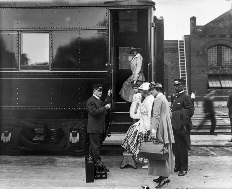 Women boarding a train with assistance by a Pullman porter (on the right) and a conductor (on the left), circa 1915.